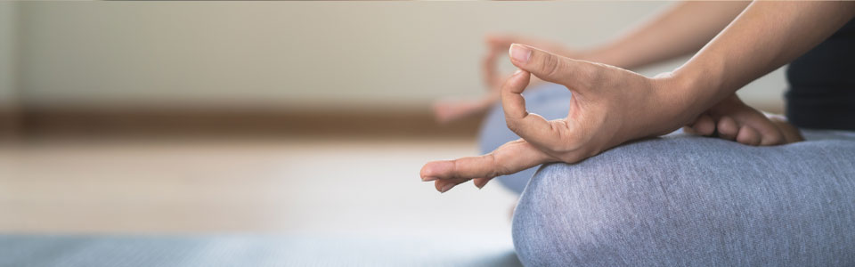 Meditation in entspannter Pose Nahaufnahme einer Person im Schneidersitz, meditierend auf einer Yogamatte, Hände in mudra-Position.
