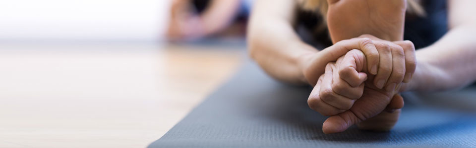 Frau beim Yoga-Stretching Nahaufnahme einer Frau, die auf einer Yogamatte eine Dehnübung macht