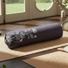 Yogaraum mit bestickter Rolle Eine bestickte Yogarolle liegt auf einer Matte in einem hellen Raum.