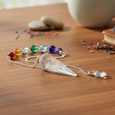Pendelkette mit Kristall und bunten Perlen Eine Pendelkette aus Kristall mit bunten Perlen auf einem Holztisch