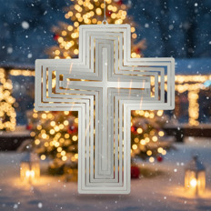 Weihnachtskreuz vor beleuchtetem Baum Ein dekoratives Kreuz vor einem verschwommenen, festlich beleuchteten Baum im Schnee.