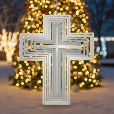 Kreuz vor beleuchtetem Weihnachtsbaum Ein metallisches Kreuz hängt vor einem verschwommenen, beleuchteten Weihnachtsbaum im Hintergrund.