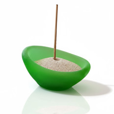 Grüne Kerzenschale mit Sand und Stäbchen Grüne Kerzenschale gefüllt mit Sand und einem aufrecht stehenden Räucherstäbchen.