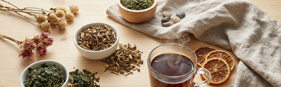 Kräutertee und Zutaten Arrangement Bild von Kräutertee und getrockneten Zutaten auf einem Tisch, inklusive Kräutern in Schalen und getrockneten Orangenscheiben.