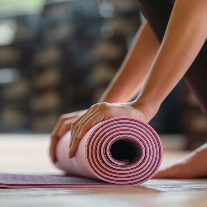 Nahaufnahme einer Person, die eine rosa Yogamatte aufrollt.