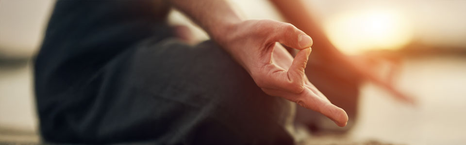 Nahaufnahme einer Hand in Meditationspose bei Sonnenuntergang
