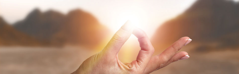 Hand in Meditationsgeste vor Sonnenuntergang in der Natur