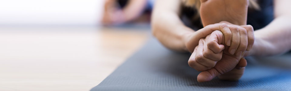 Nahaufnahme einer Frau, die auf einer Yogamatte eine Dehnübung macht