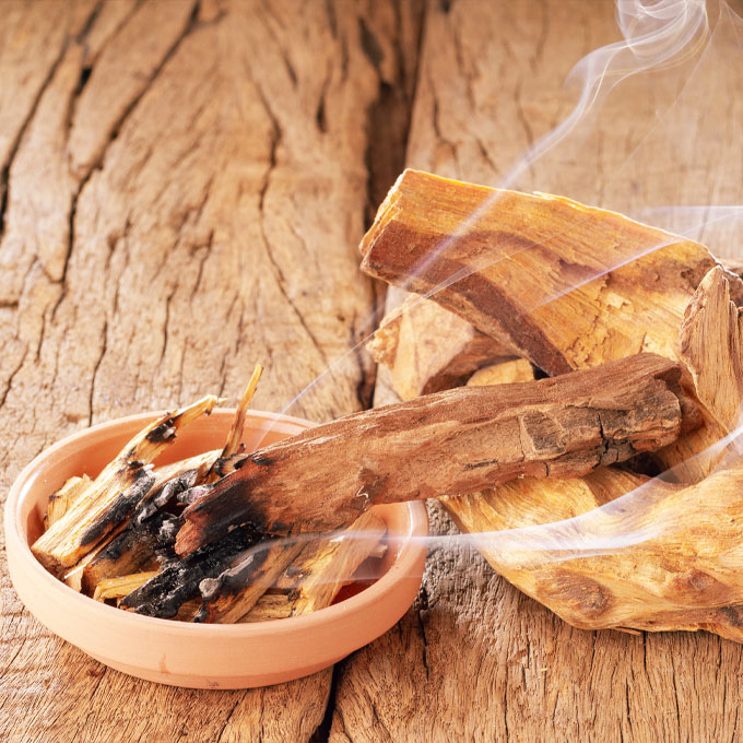 Bild von rauchendem Holz in einer Schale auf Holztisch.