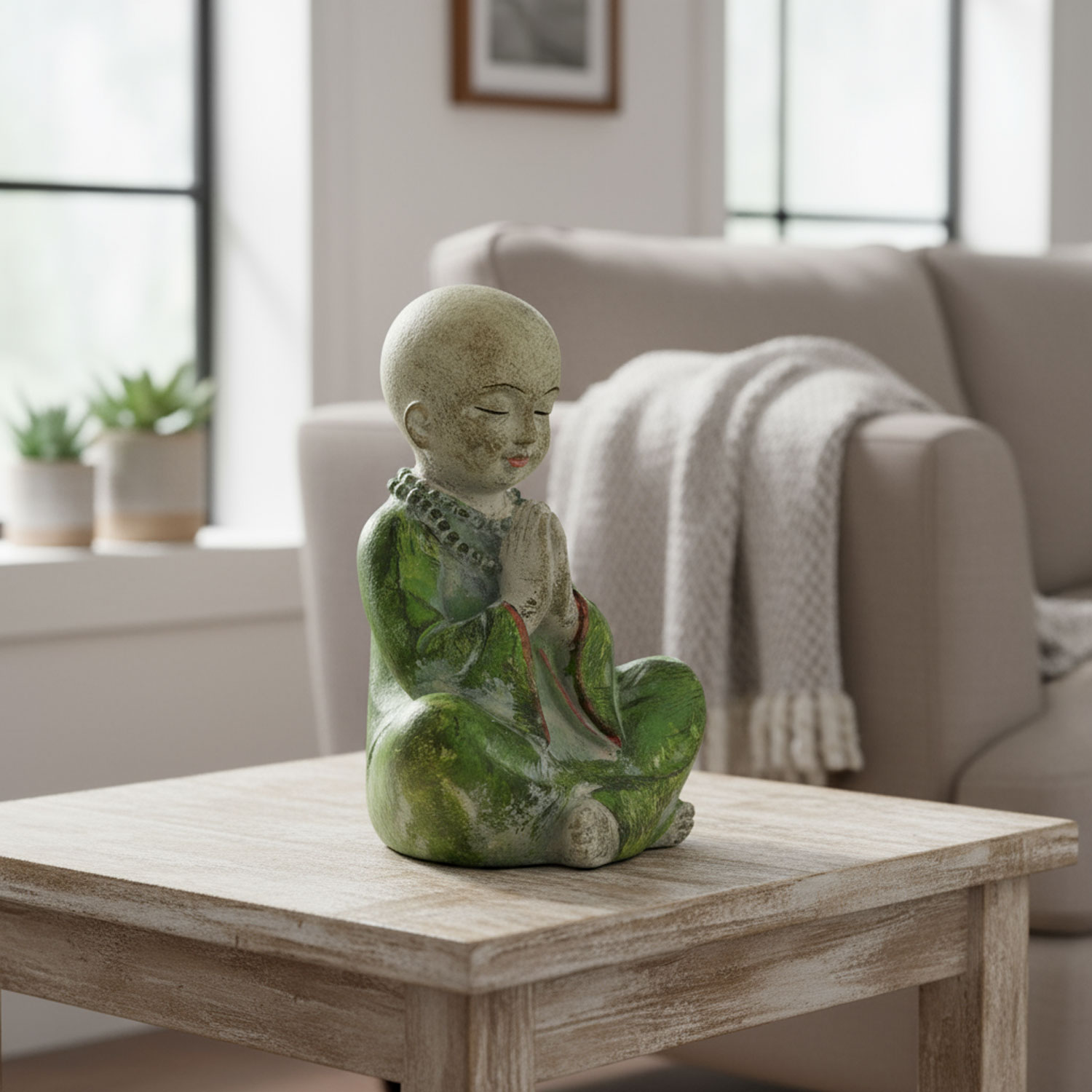 Tonfigur eines meditierenden Kindes in grüner Robe auf einem Holztisch im Wohnzimmer