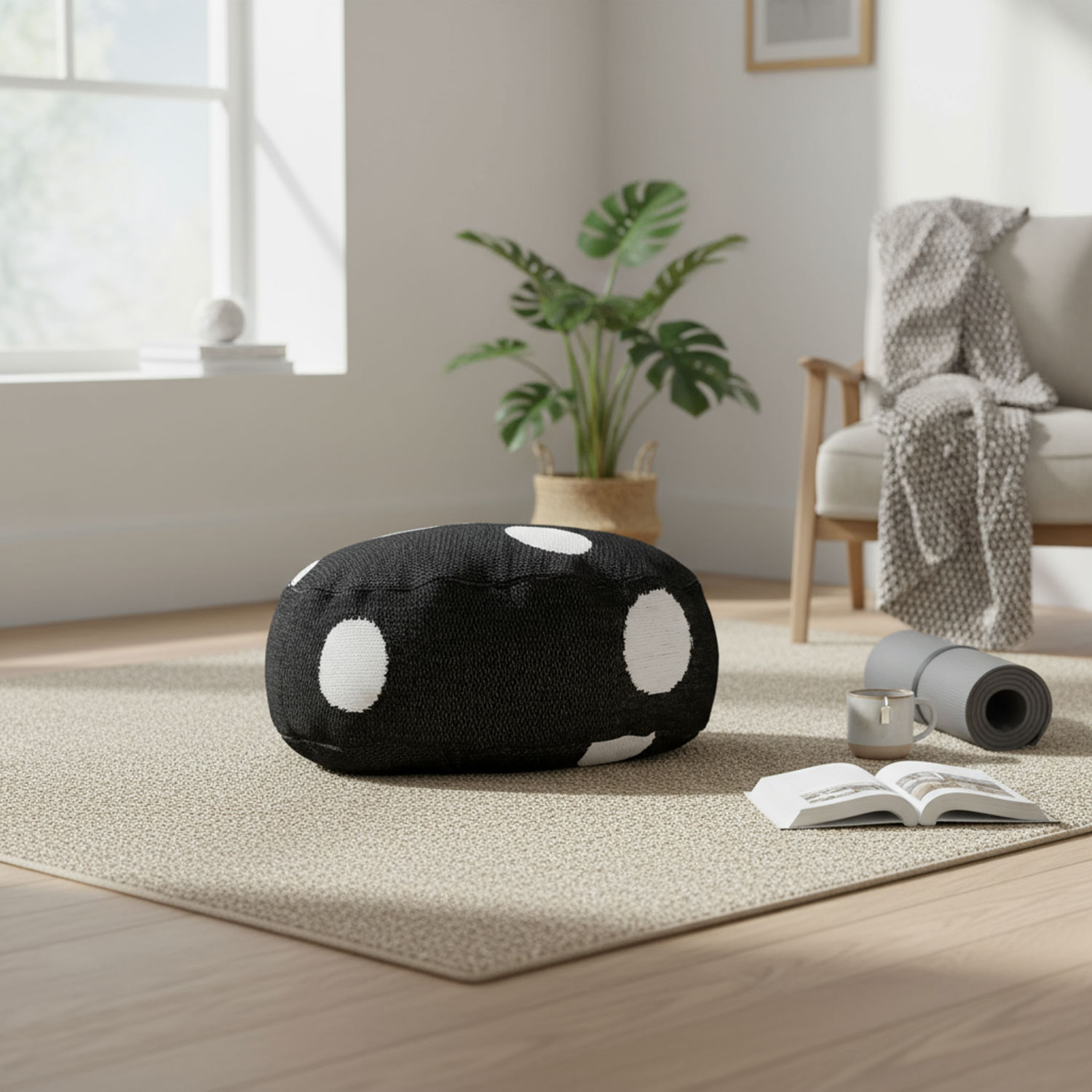 Wohnzimmer mit großem Fenster, schwarzem Pouf mit weißen Punkten, Pflanze, Teppich, Yoga-Matte, Tasse und offenem Buch.