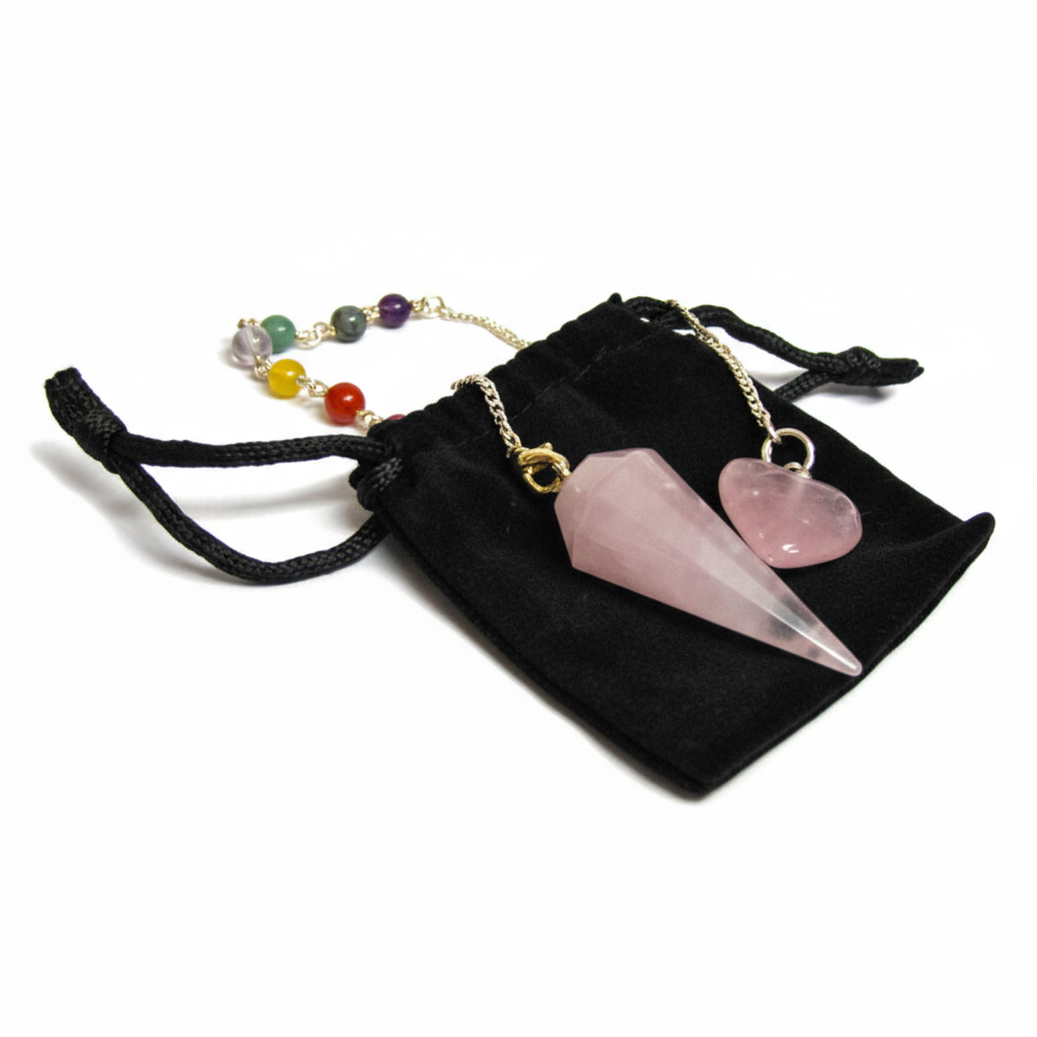 Ein Rosenquarz Pendel und ein Herzanhänger auf einem schwarzen Samtbeutel mit einer Perlenkette im Hintergrund.