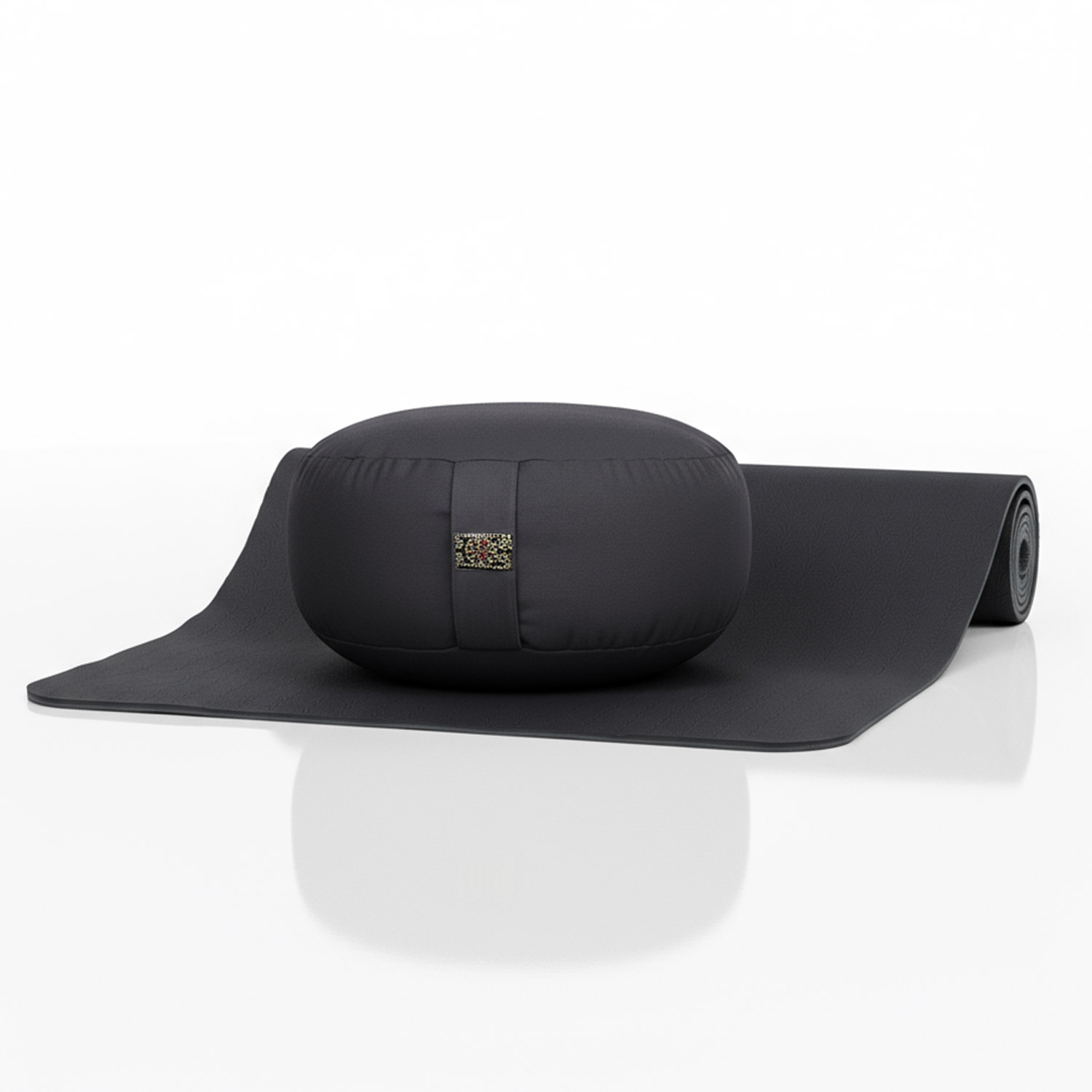 Eine aufgerollte graue Yoga Matte und ein rundes Meditationskissen in Dunkelgrau