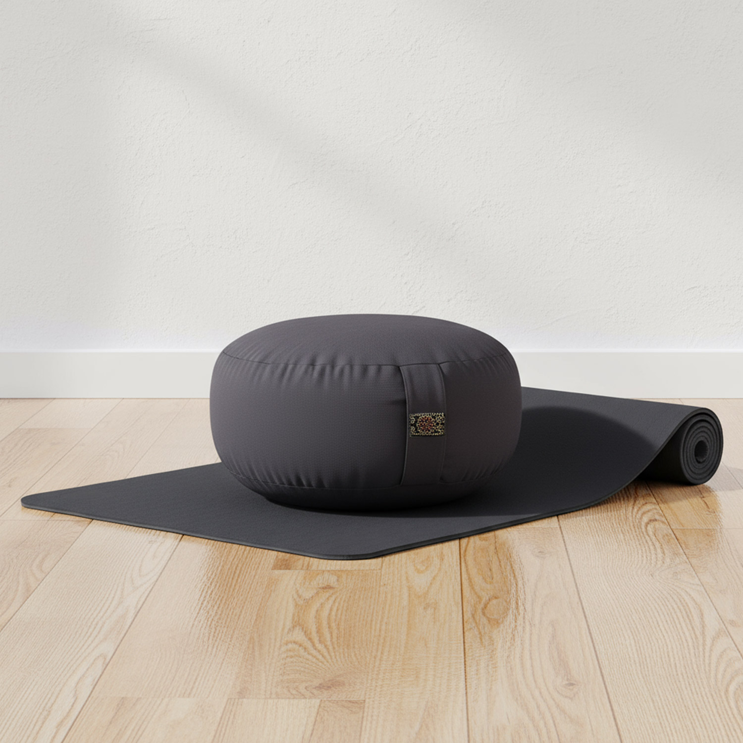 Ein graues Meditationskissen auf einer ausgerollten Yogamatte auf Holzboden.