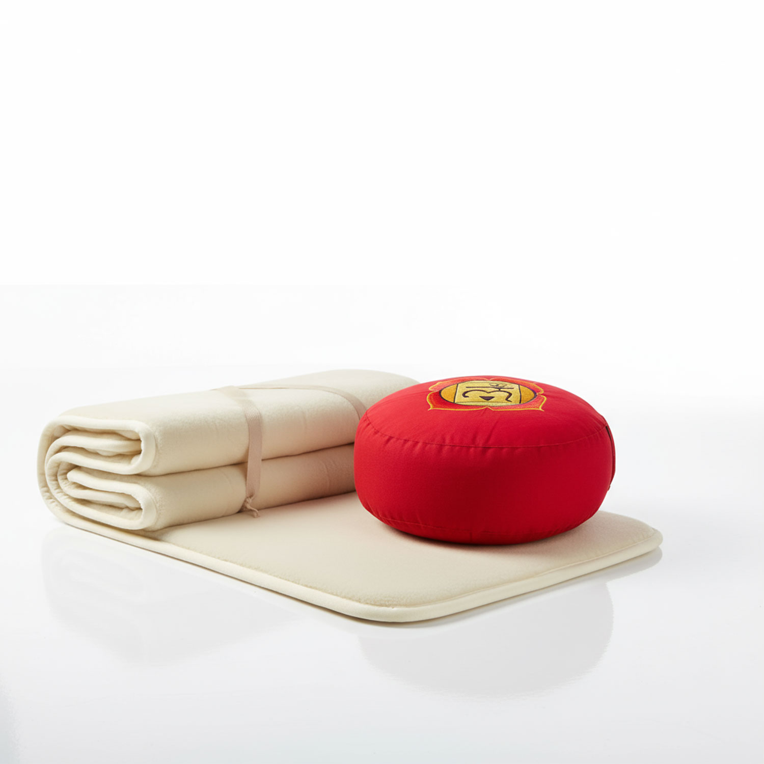 Ein beiges Meditationskissen und eine gefaltete matte mit einem roten meditfaches Kissen darauf, auf weißem Hintergrund.