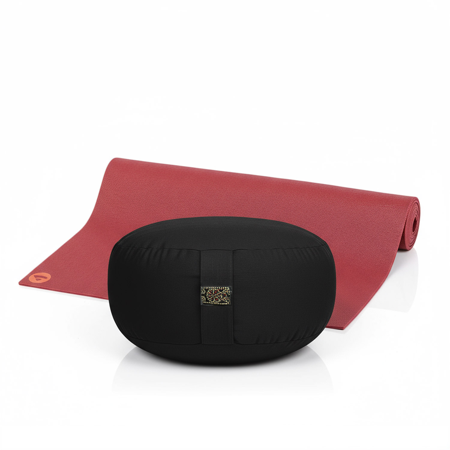 Ein schwarzes Meditationskissen vor einer roten Yogamatte