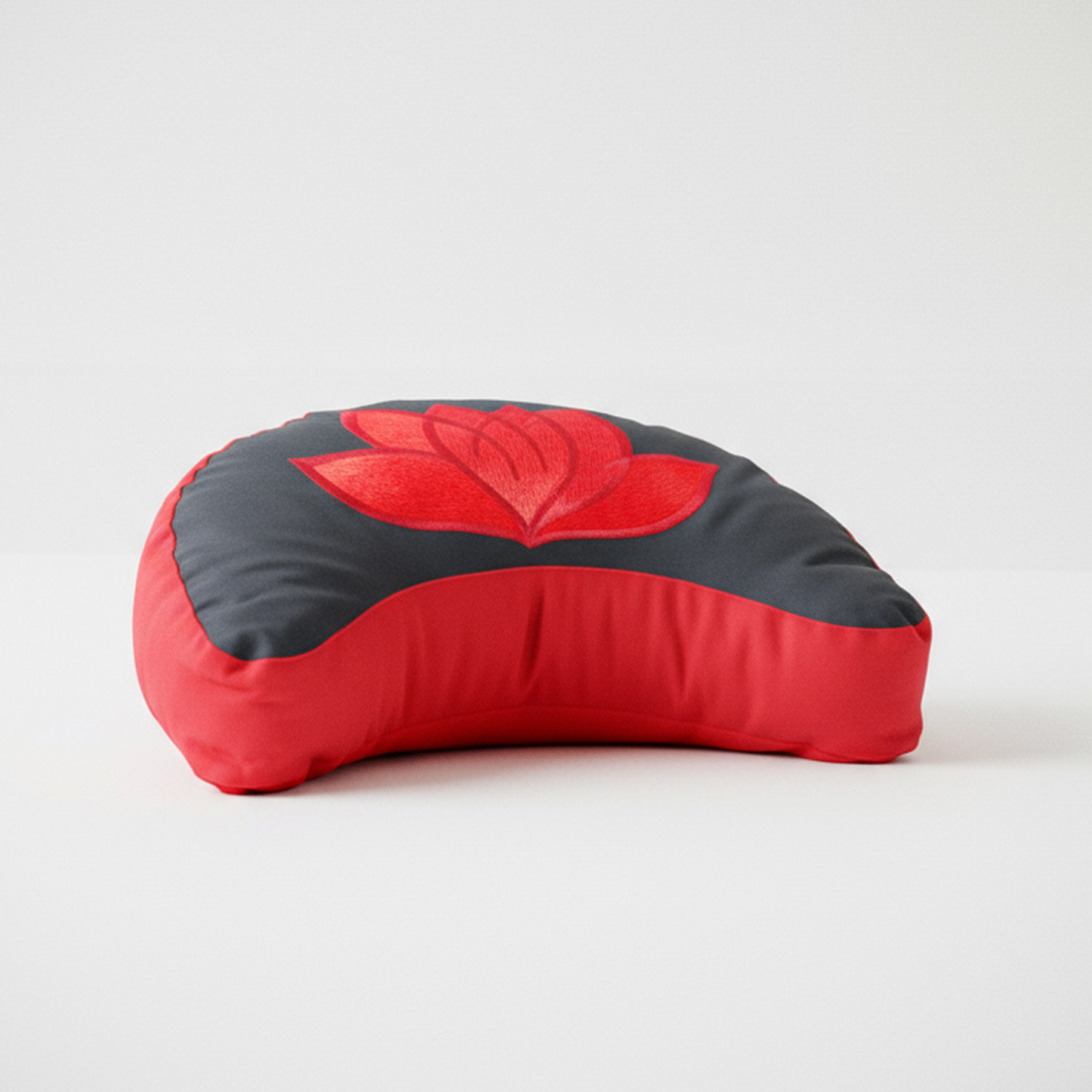Rotes Meditationskissen mit eingestickter Lotusblüte auf einer grauen Oberfläche