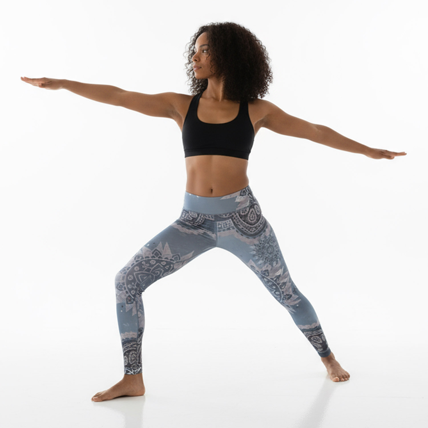 Frau in Sportkleidung führt die Kriegerpose im Yoga aus