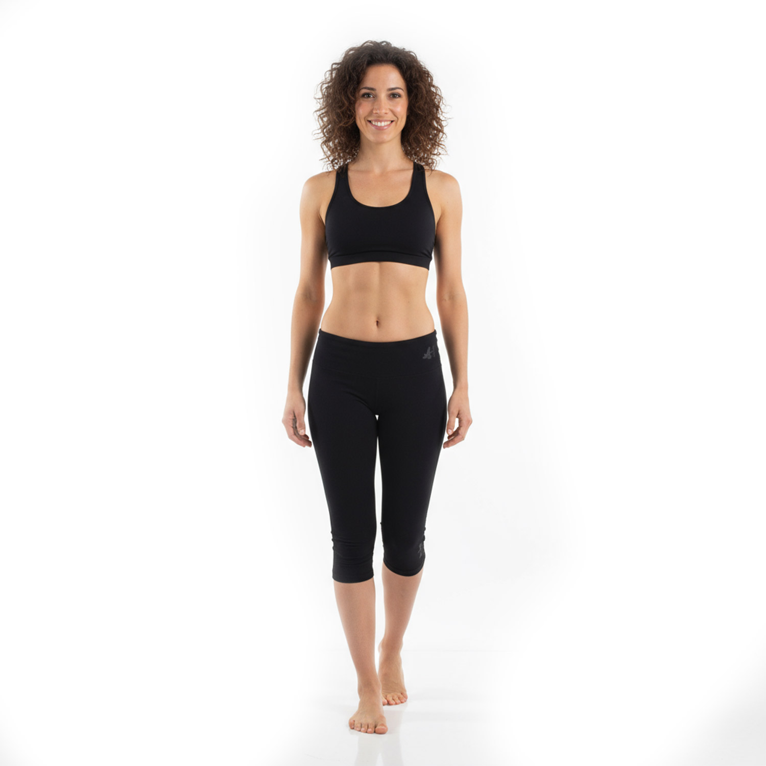 Frau mit lockigem Haar in schwarzem Sport-BH und Leggings