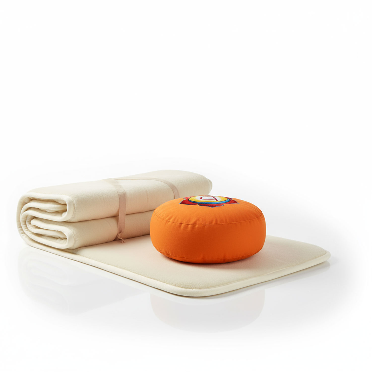Ein orangefarbenes Meditationskissen und eine zusammengefaltete beige Decke auf einem weißen Untergrund.