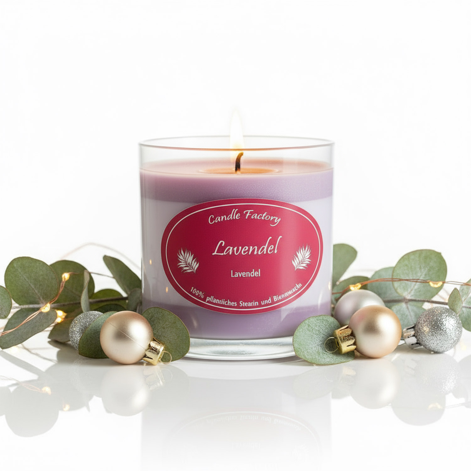 Brennende Lavendelduftkerze in Glas mit Eukalyptus und Christbaumschmuck