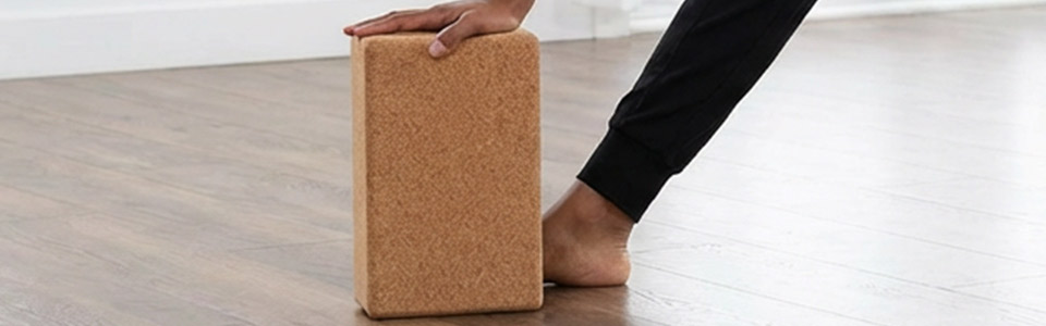 Person verwendet einen Korkblock während einer Yoga-Übung.
