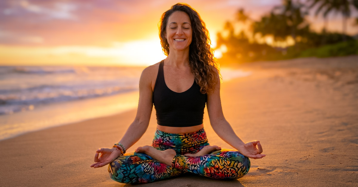 Yogini meditiert auf Yogamatte bei Sonnenaufgang am Strand, umgeben von Palmen und sanften Wellen, symbolisiert Ruhe und Erholung im Yoga-Urlaub.
