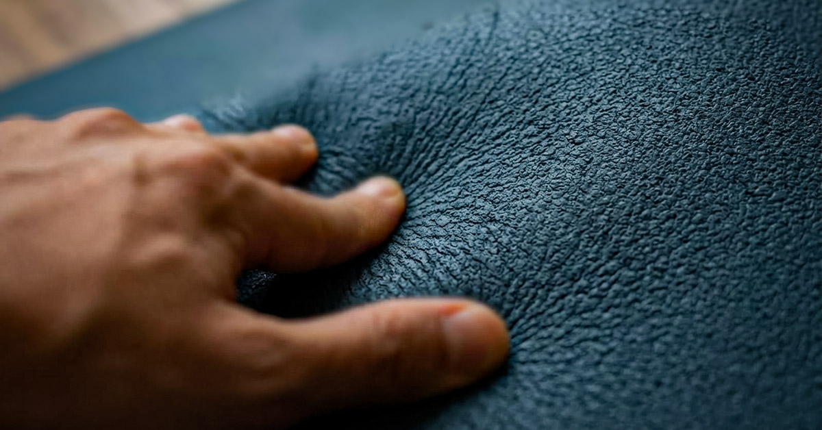 So griffig ist Naturkautschuk Eine Hand drückt auf die raue, griffige Oberfläche einer Yogamatte aus Naturkautschuk, was die ausgezeichnete Rutschfestigkeit verdeutlicht.