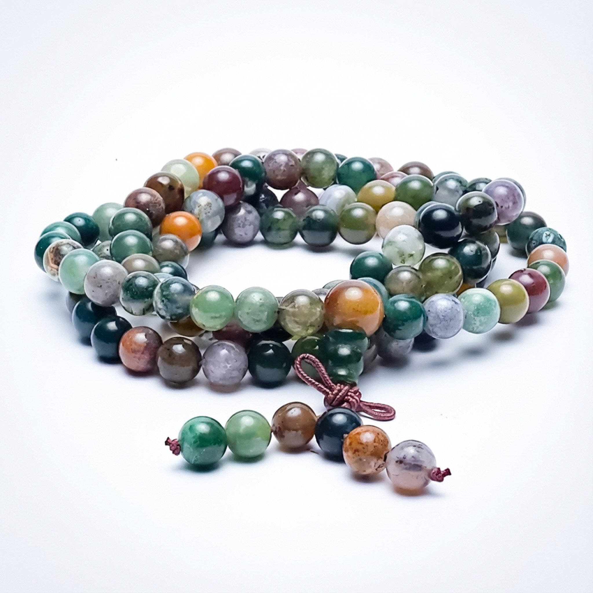 Eine bunte Perlenkette aus verschiedenen Edelsteinen auf einem weißen Hintergrund.