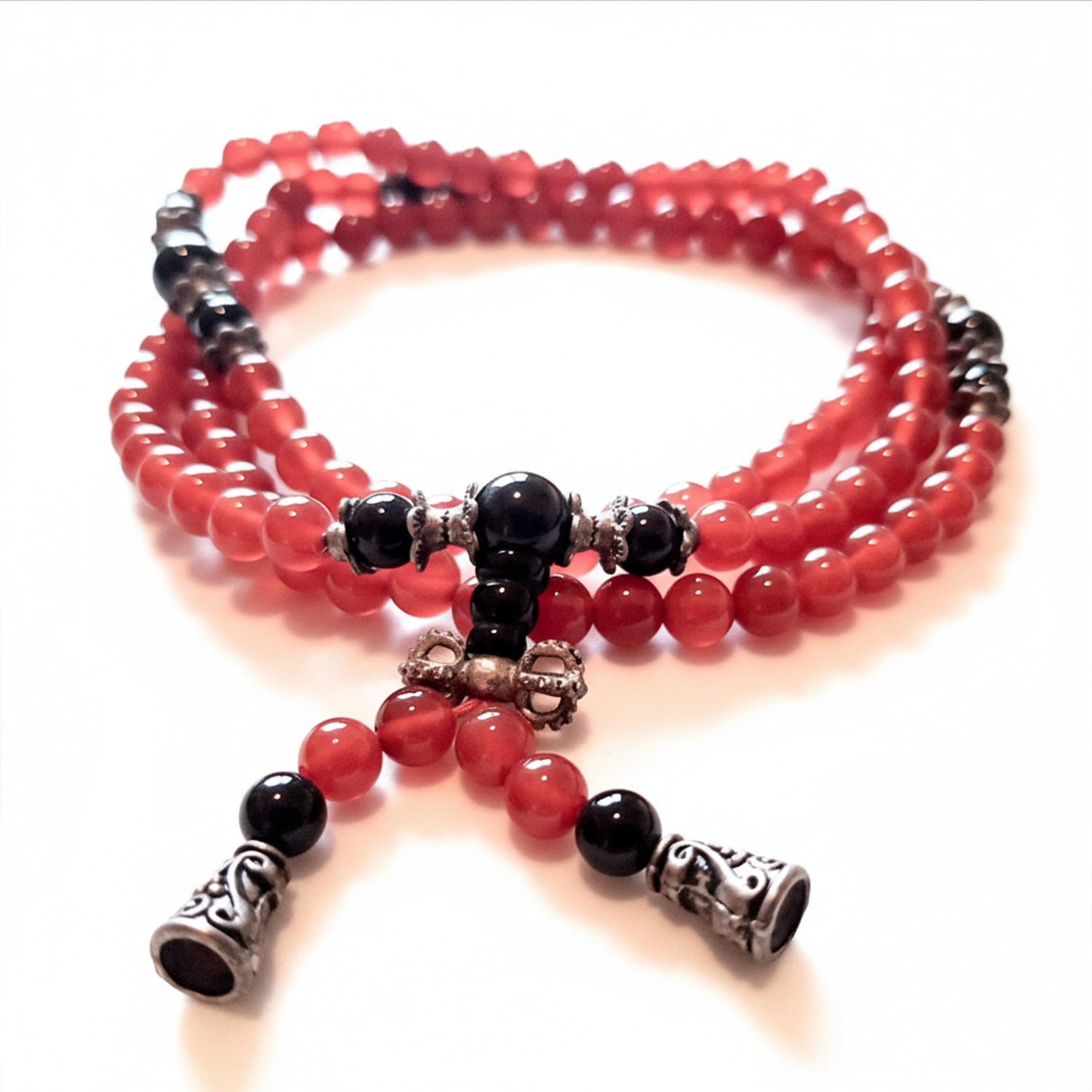 Mehrreihige rote Gebetskette mit schwarzen Perlen und silberfarbenen Metallverzierungen auf hellem Hintergrund