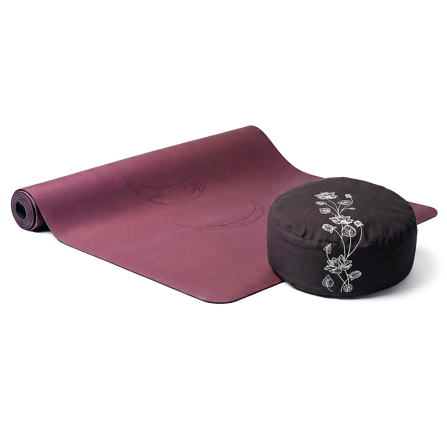 Eine ausgerollte violette Yogamatte neben einem dunklen Meditationskissen mit floralem Muster