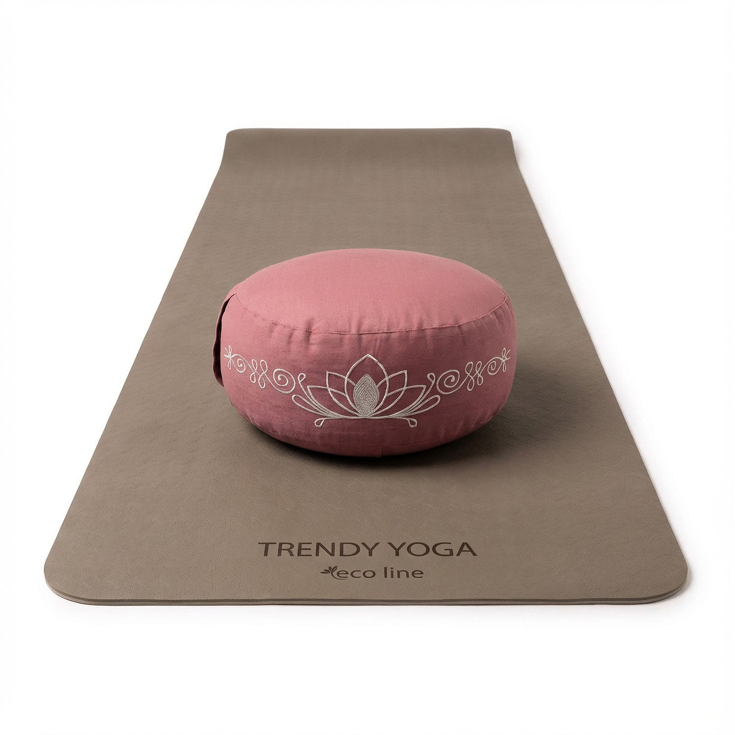 Eine braune Yogamatte mit einem rosafarbenen Meditationskissen mit Lotusmotiv darauf.
