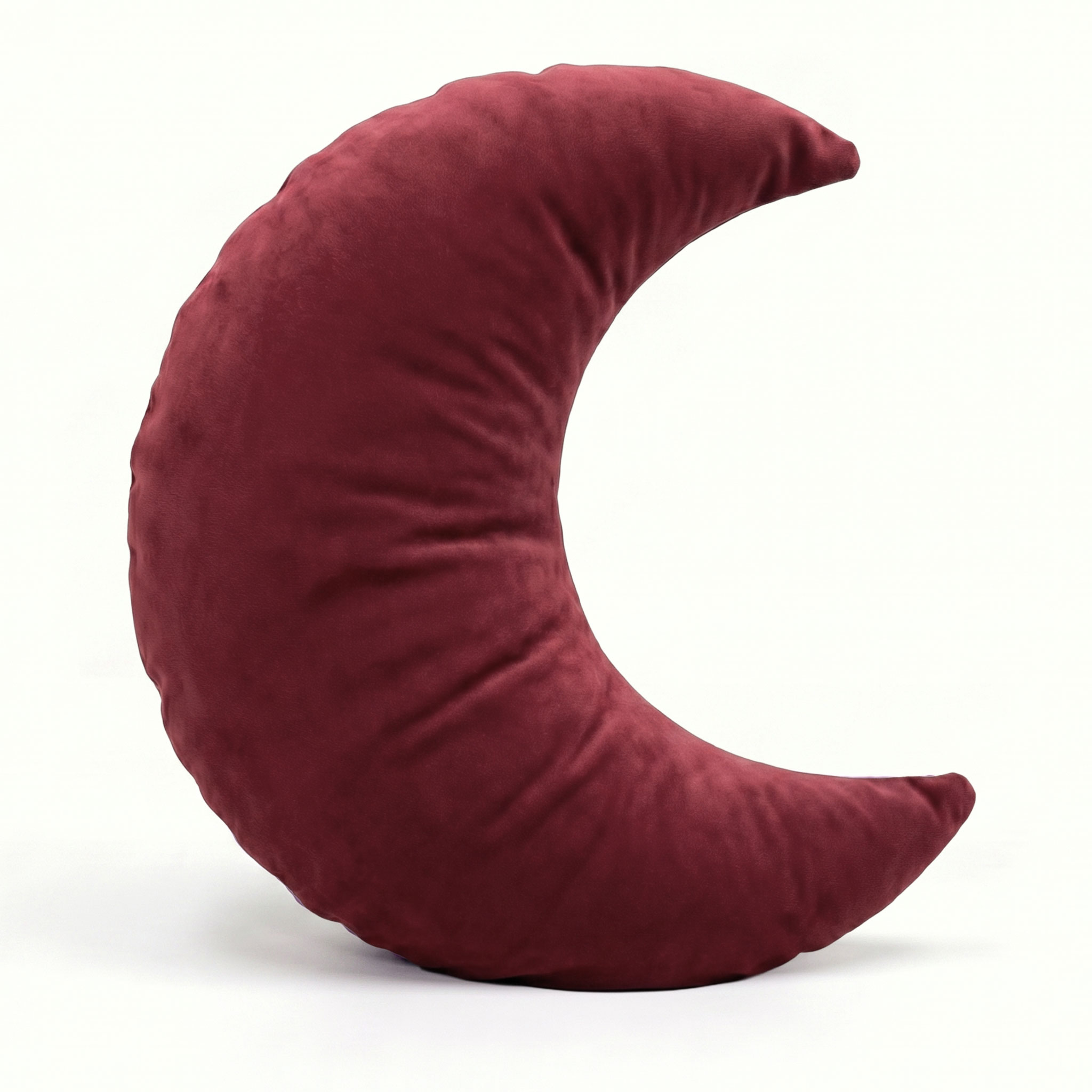 Ein burgunderrotes Kissen in Halbmondform vor hellem Hintergrund