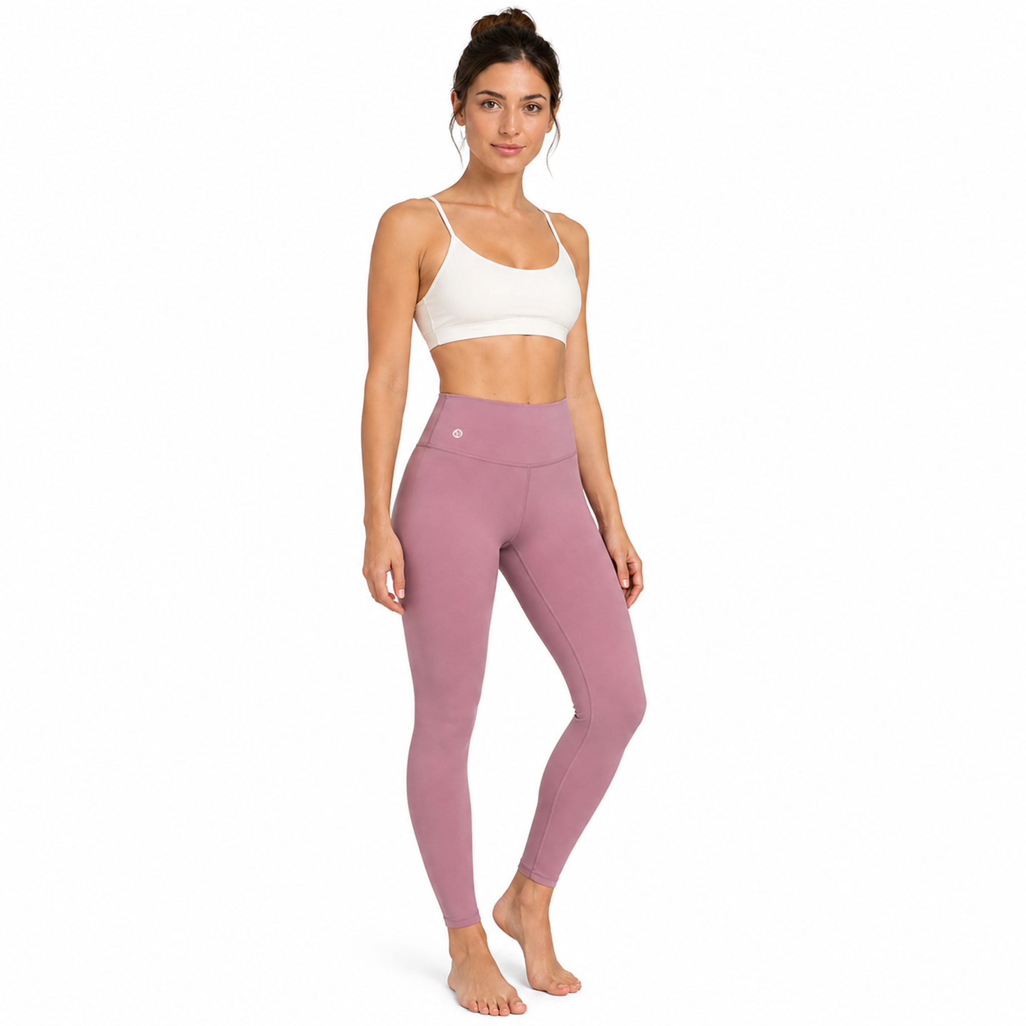 Eine Frau steht aufrecht und trägt einen weißen Sport-BH sowie rosafarbene Leggings.