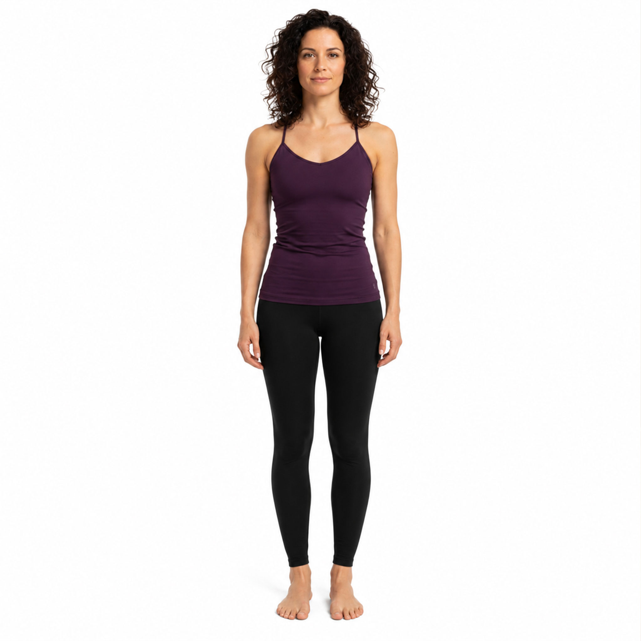 Eine Frau steht barfuß frontal und trägt ein lilafarbenes Sporttop und schwarze Leggings