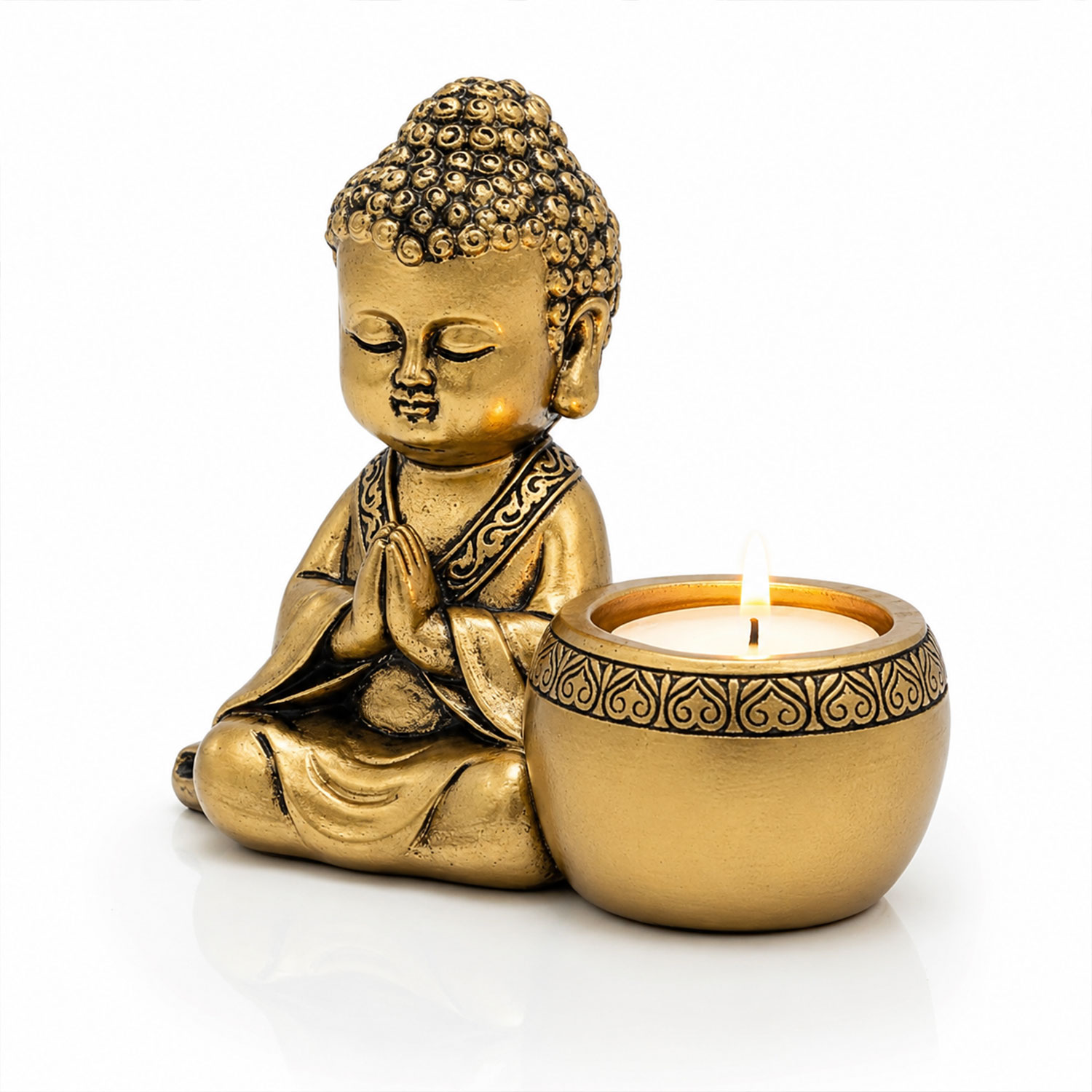 Goldene Buddha-Figur in Gebetshaltung neben einer brennenden Kerze auf hellem Hintergrund
