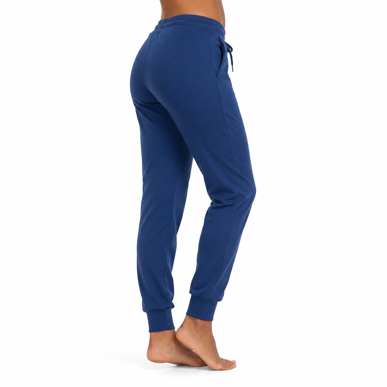 Rückansicht einer Person mit blauer Jogginghose und nackten Füßen vor hellem Hintergrund.