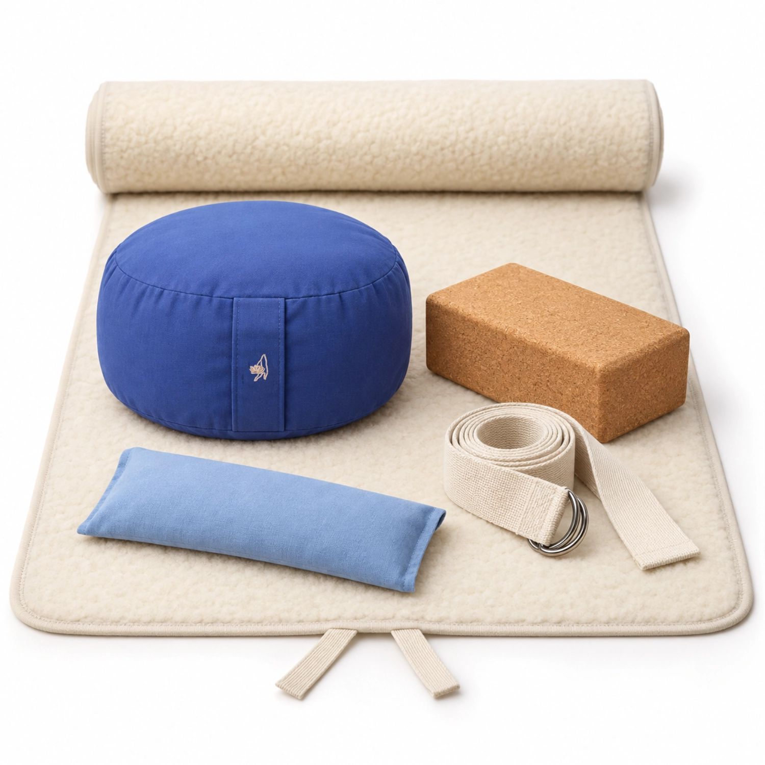 Meditations- und Yogazubehör mit blauem Sitzkissen, Korkblock, Gurt und kleinem Kissen auf einer cremefarbenen, gepolsterten Matte